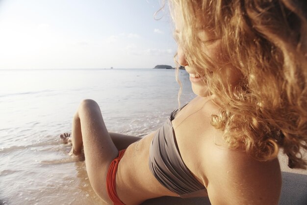 Menina bonita corre ao longo da praia em um bikini tan férias de verão