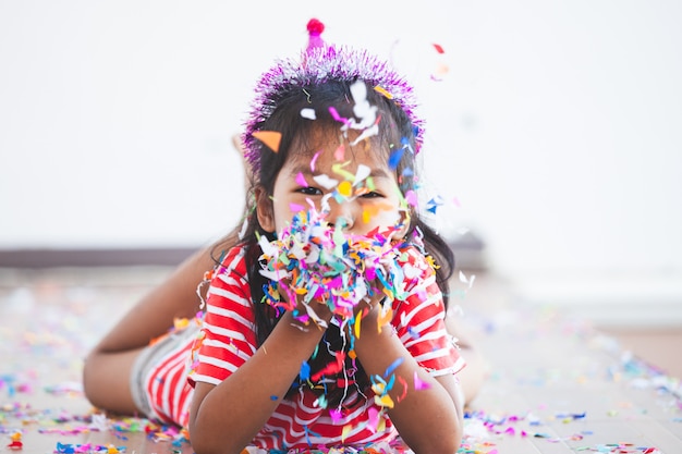Menina bonita criança asiática com confetes coloridos para comemorar em sua festa