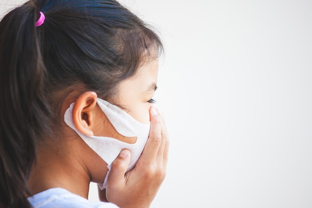 Menina bonita criança asiática usando máscara de proteção contra a poluição atmosférica