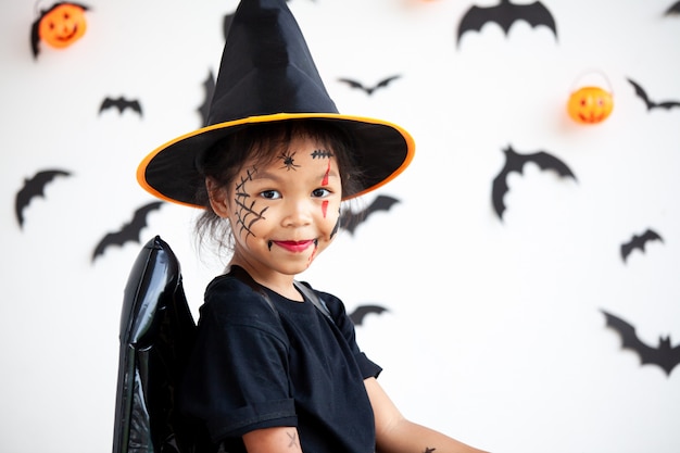 Menina bonita criança asiática vestindo maquiagem e trajes de halloween se divertindo na celebração do dia das bruxas