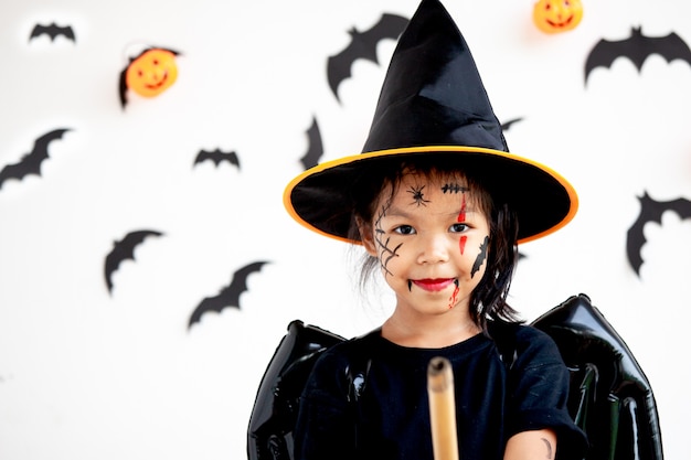 Menina bonita criança asiática vestindo maquiagem e trajes de halloween se divertindo na celebração do Dia das Bruxas