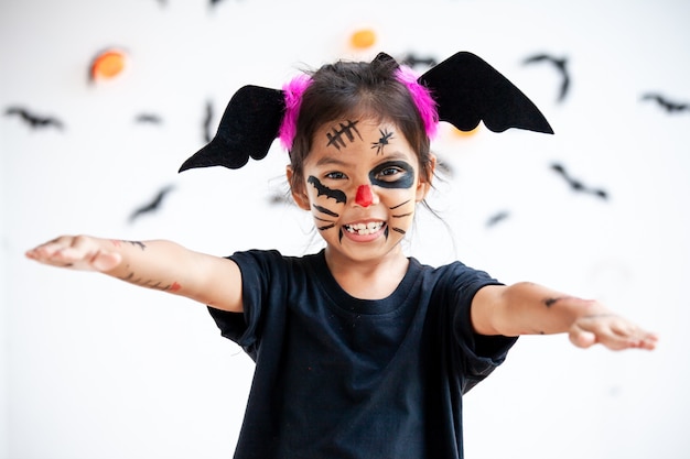 Menina bonita criança asiática vestindo maquiagem e trajes de halloween se divertindo na celebração do dia das bruxas