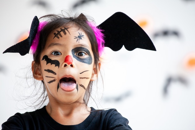 Menina bonita criança asiática vestindo maquiagem e trajes de halloween se divertindo na celebração do dia das bruxas