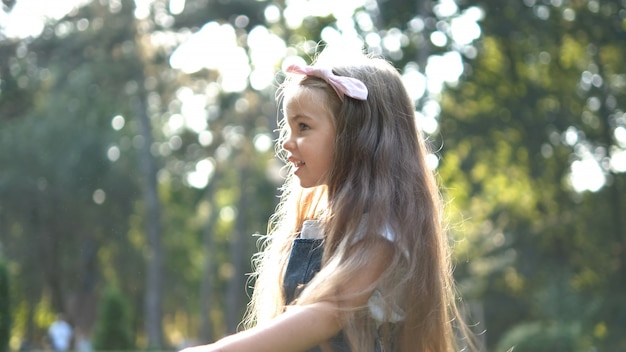 Menina bonita criança caminhando ao ar livre no parque verde de verão.