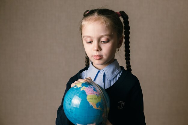 Menina bonita criança olha o globo