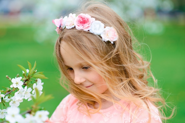 Menina bonita criança sorrindo e brincando nas flores do jardim, árvores florescendo, cereja, maçãs.