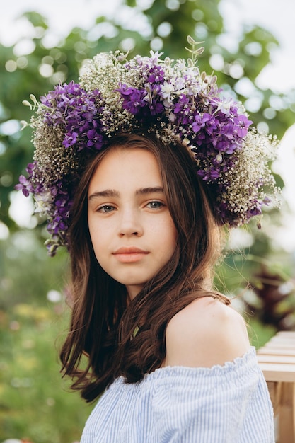 Menina bonita de 13 anos carregando cesta de lindas flores no campo de flores com felicidade