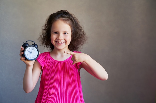 Foto menina bonita de cabelos cacheados com um relógio