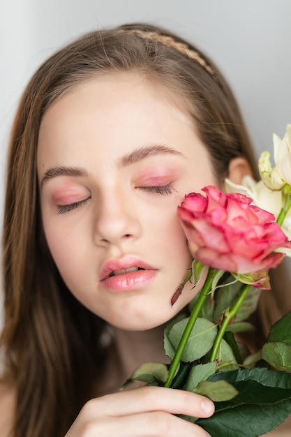 Menina bonita de rosa segura o buquê de rosas feche as flores e enfrente a pequena bailarina com um buquê