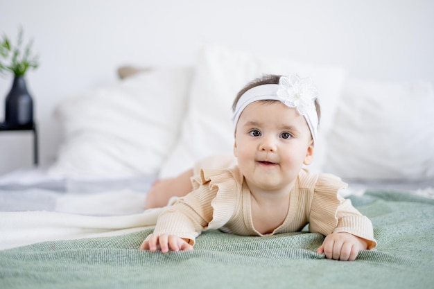 Menina bonita de seis meses em uma cama verde em casa sorrindo feliz recém-nascido