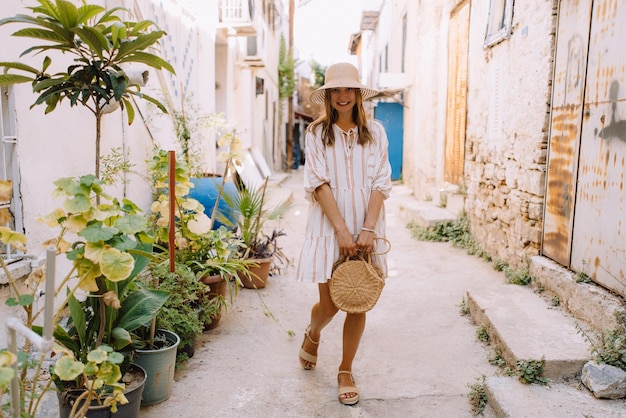 Menina bonita de vestido e chapéu anda pelas ruas antigas