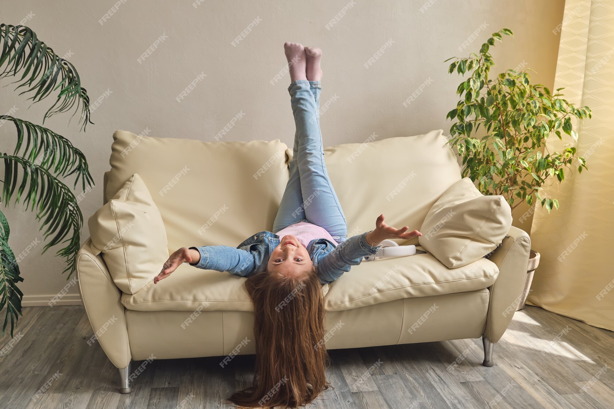 Sorridente menina deitada no sofá confortável, gostando de jogar