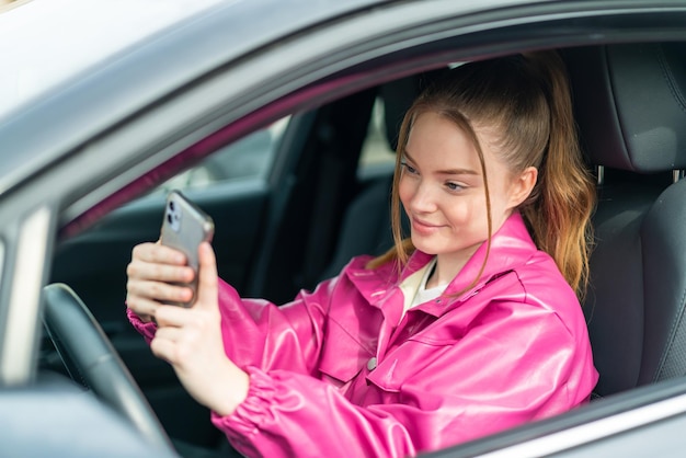 Menina bonita dentro de um carro usando telefone celular