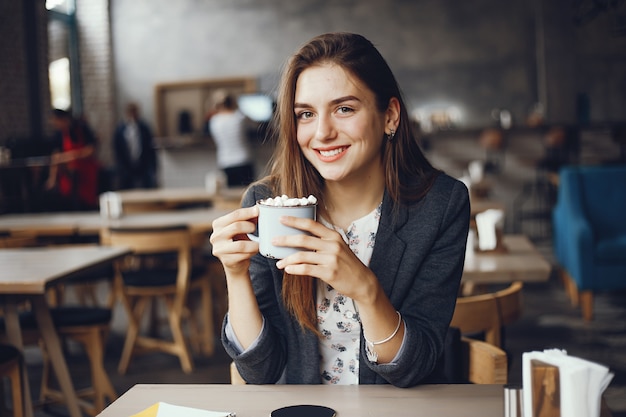 Menina bonita e elegante, sentado em um café e beber um café