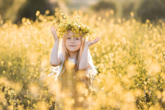 Menina bonita e estilosa usa guirlanda floral em prado de flores amarelas ao ar livre sobre natur