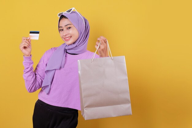 Menina bonita e feliz sorridente usando cartão de crédito para desperdiçar algum dinheiro no shopping, segurando sacolas de compras, comprar presentes ou presentes, mimar-se, rir com alegria