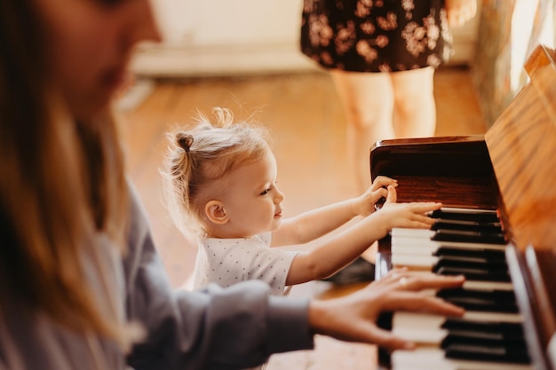 Menina bonita e feliz tocando piano em uma sala de luz Efeito de ruído de foco seletivo