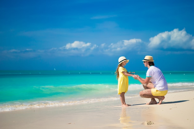 Menina bonita e seu pai na praia exótica tropical
