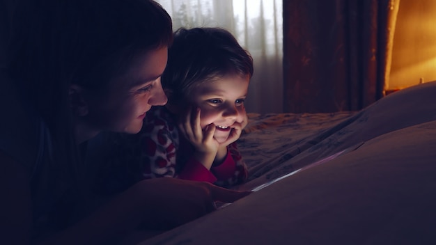 Menina bonita e sua mãe assistindo tablet