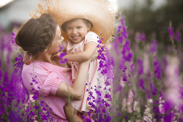 Menina bonita e sua mãe com flores. Família ao ar livre