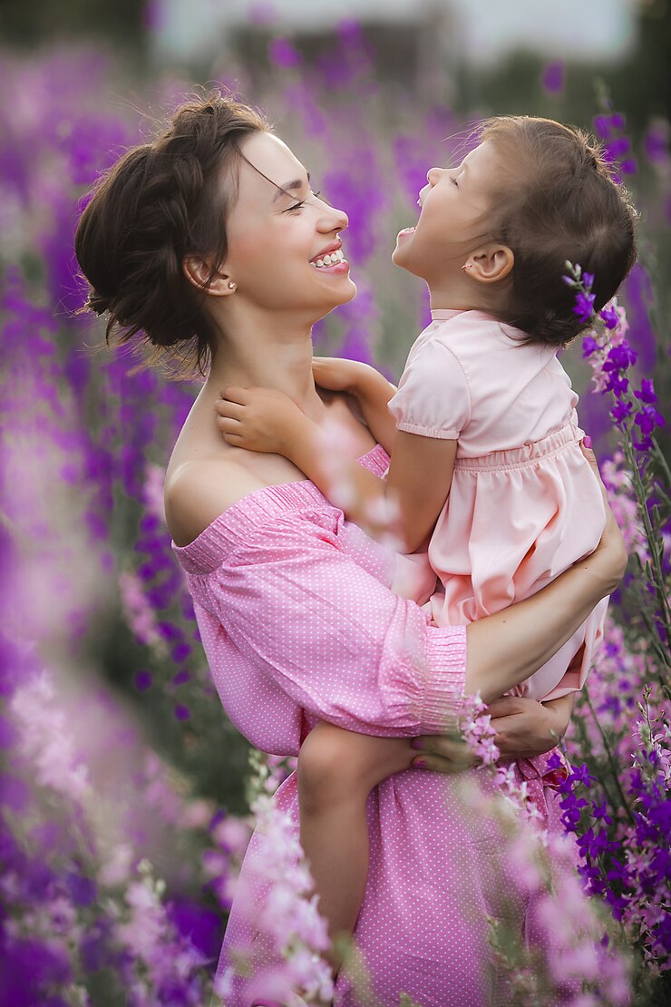 Menina bonita e sua mãe com flores. Família ao ar livre