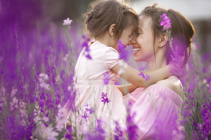 Menina bonita e sua mãe com flores. Família ao ar livre
