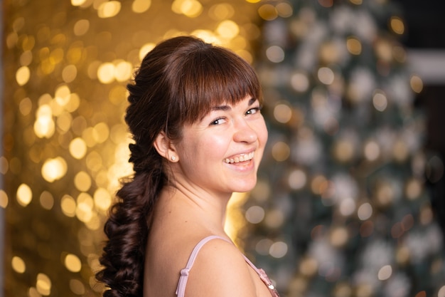 Menina bonita elegante entre brilhos e gerlands em uma festa de natal.