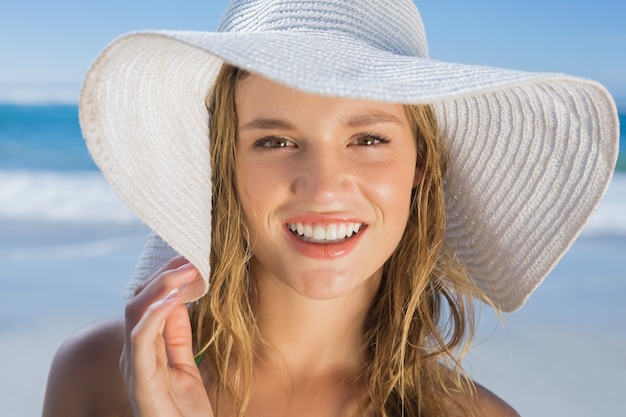 Menina bonita em chapéu de palha na praia sorrindo na câmera