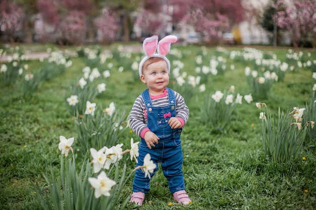 Menina bonita em pé na grama perto dos narcisos