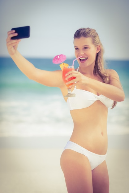 Menina bonita em swimsuit tomando uma selfie