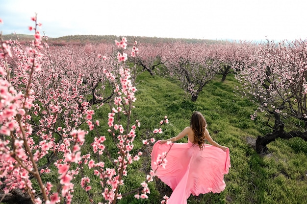 Menina bonita em um jardim de primavera florescendo. mulher dresed em um vestido de noiva