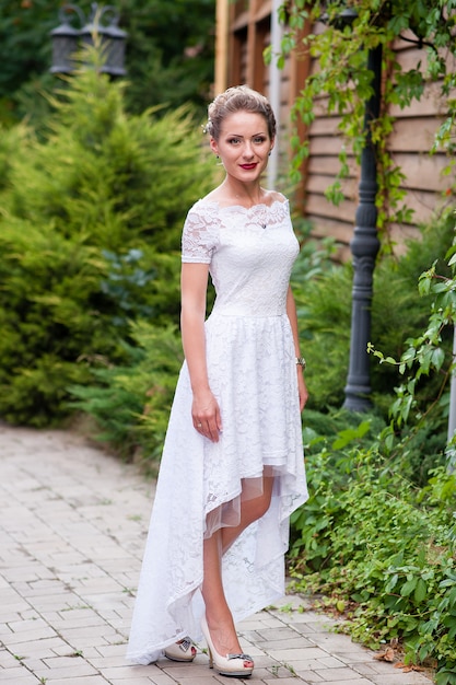 Foto menina bonita em um vestido branco ao ar livre.