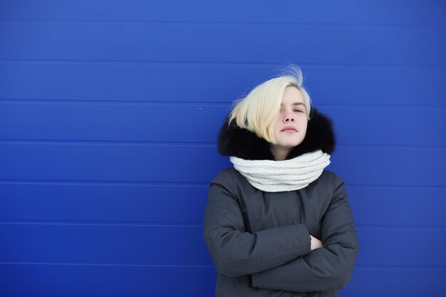 Menina bonita em uma caminhada no inverno no fundo da parede azul