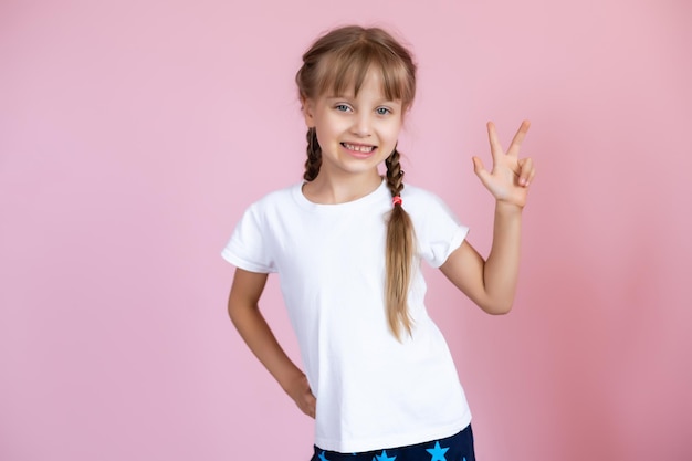 Menina bonita em uma camiseta branca sorrindo em um fundo rosa