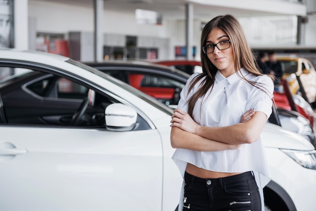 Menina bonita está de pé perto de seu carro.