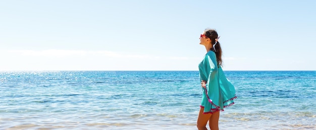Menina bonita está posando em um vestido azul no fundo do mar Conceito de férias felizes