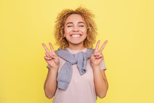 Menina bonita está sorrindo e mostrando um símbolo de peça com os dedos nas mãos dela.