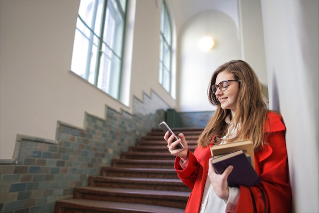 Menina bonita estudante verificando seu smartphone