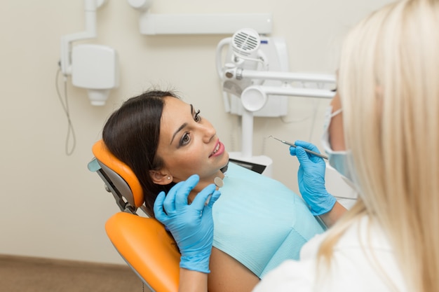 Menina bonita, fazendo exame de boca no hospital pelo dentista profissional feminino