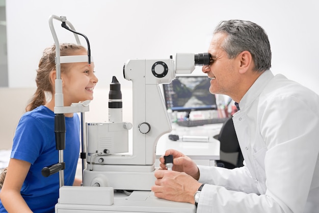 Menina bonita fazendo exame de vista em consultório médico.