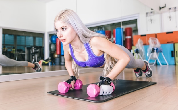 Menina bonita fazendo flexões em halteres