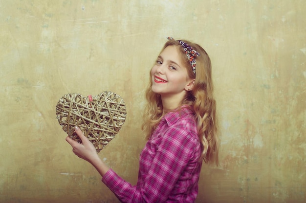 Menina bonita feliz com coração de vime para dia dos namorados