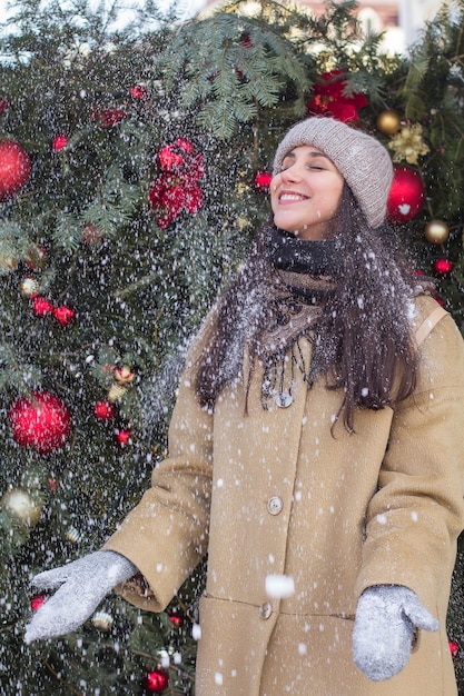 Menina bonita feliz durante as férias de Natal em luvas está nevando