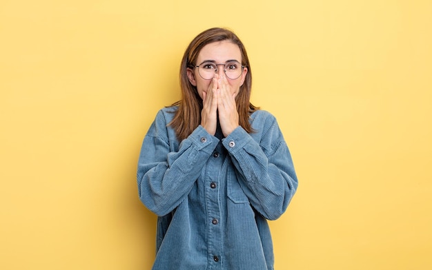 Menina bonita feliz e animada, surpresa e maravilhada cobrindo a boca com as mãos, rindo com uma expressão fofa