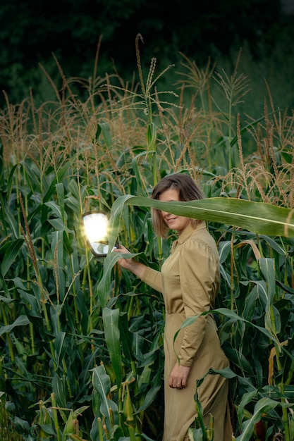 Menina bonita feliz segurando um espelho e caminha e posando nos matagais de um campo de milho Beleza e moda