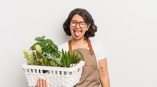 Menina bonita hispânica com atitude alegre e rebelde brincando e enfiando a língua para fora do conceito de plantas