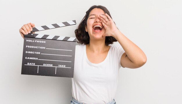 Foto menina bonita hispânica se sentindo feliz dando um grande grito com as mãos ao lado do conceito de cinema de boca