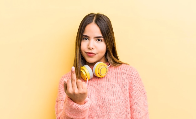 Menina bonita hispânica se sentindo irritado irritado conceito de fones de ouvido rebelde e agressivo