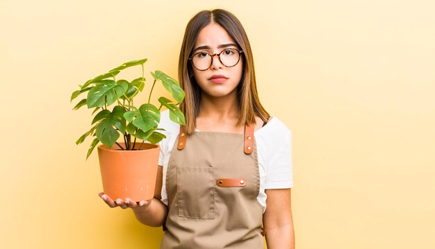 Menina bonita hispânica se sentindo triste e chorosa com um olhar infeliz e conceito de planta chorando