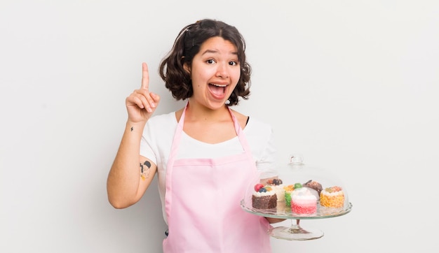 Menina bonita hispânica se sentindo um gênio feliz e animado depois de perceber uma ideia de conceito de bolos caseiros
